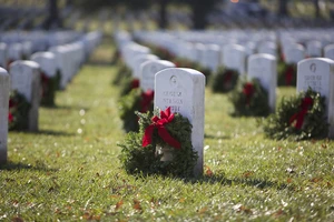 Rows of white headstones adorned with holiday wreaths honor the fallen at a national cemetery during Wreaths Across America, a moving tribute of remembrance and gratitude.